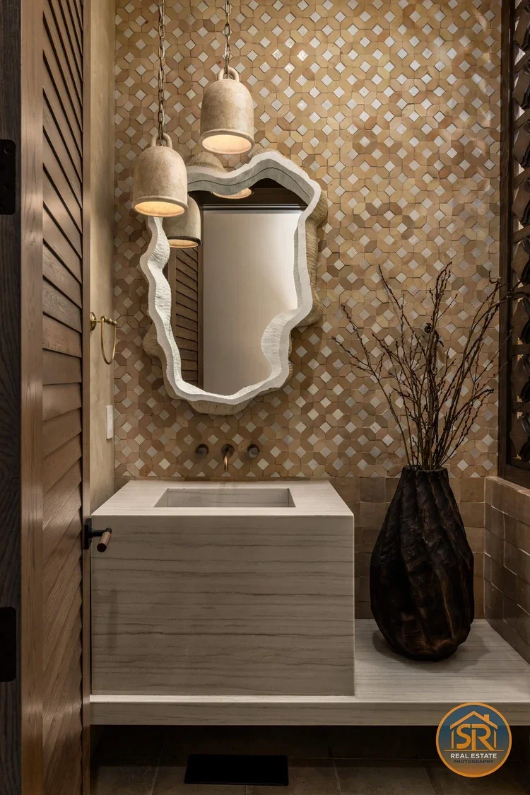 Powder room with patterned tile, pendant lights and a sculpted mirror, photographed by Sam Reed.